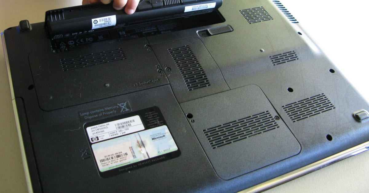 Notebook aberto com a bateria removida ao lado da carcaça
