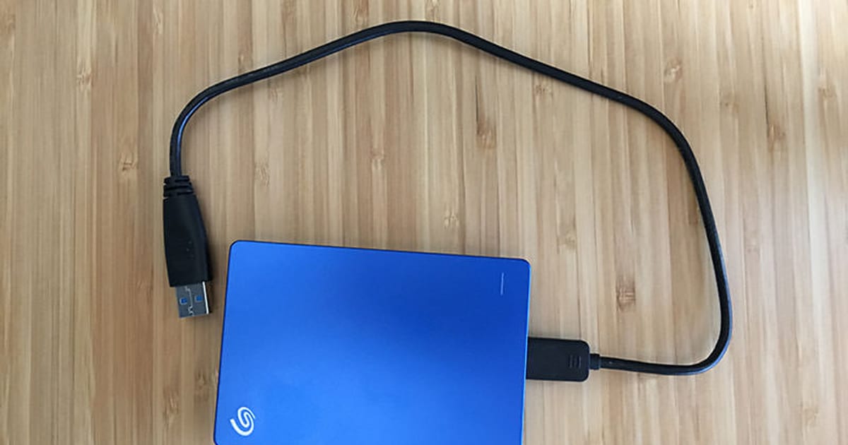 HD externo portátil conectado por cabo USB sobre uma mesa