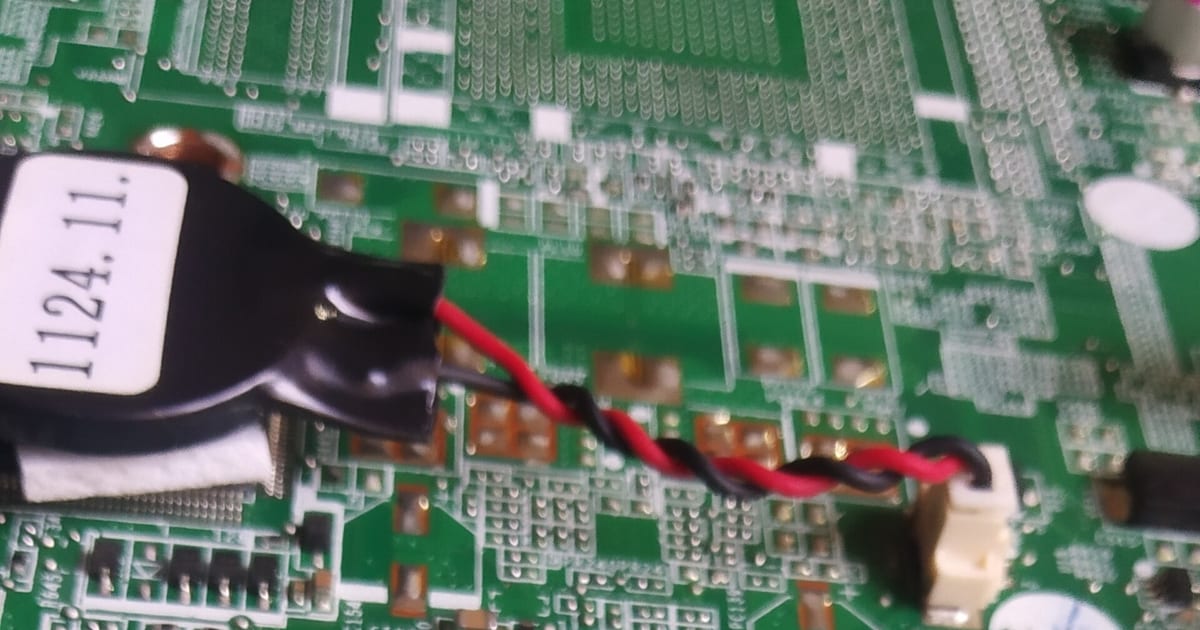 Placa-mãe de notebook com a bateria CMOS e seu par de fios conectados à placa